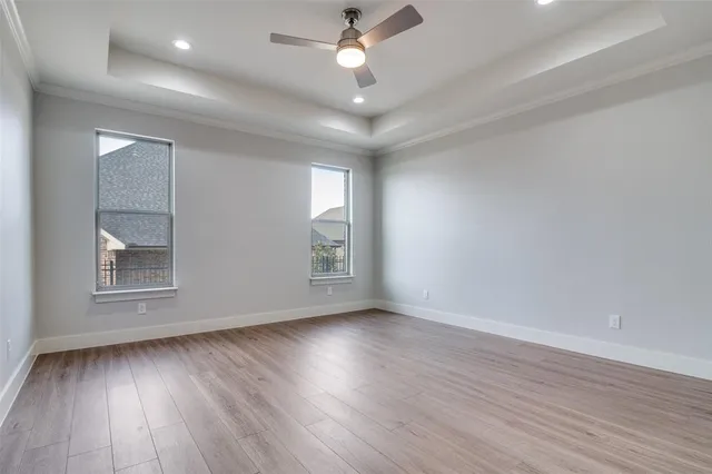 an empty room with wooden floor chandelier fan and windows