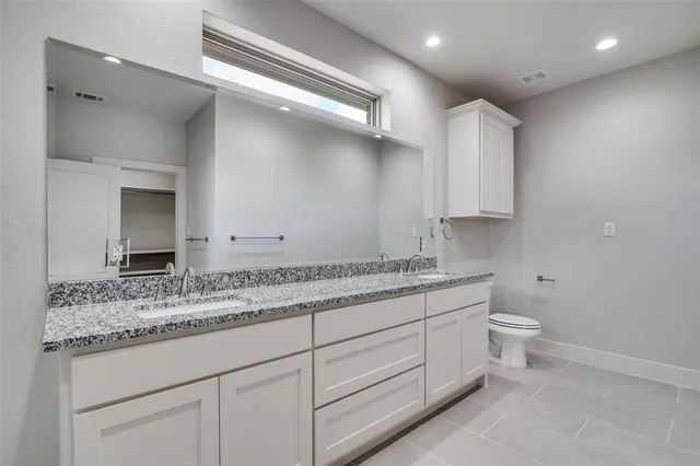 a bathroom with a granite countertop sink a toilet and a mirror