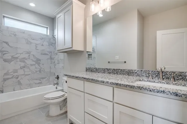 a bathroom with a granite countertop toilet a sink and bathtub