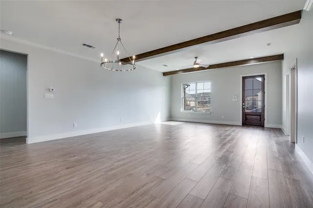 a view of a livingroom with wooden floor a ceiling fan and windows