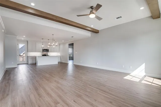 a view of empty room with wooden floor and ceiling fan
