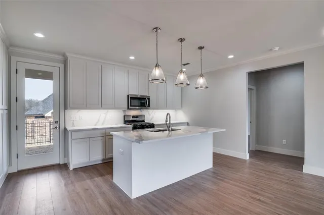 a view of a kitchen with stainless steel appliances granite countertop a stove a sink and a wooden floors