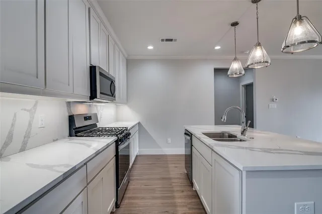 a kitchen with stainless steel appliances granite countertop a sink a stove top oven a counter space and cabinets