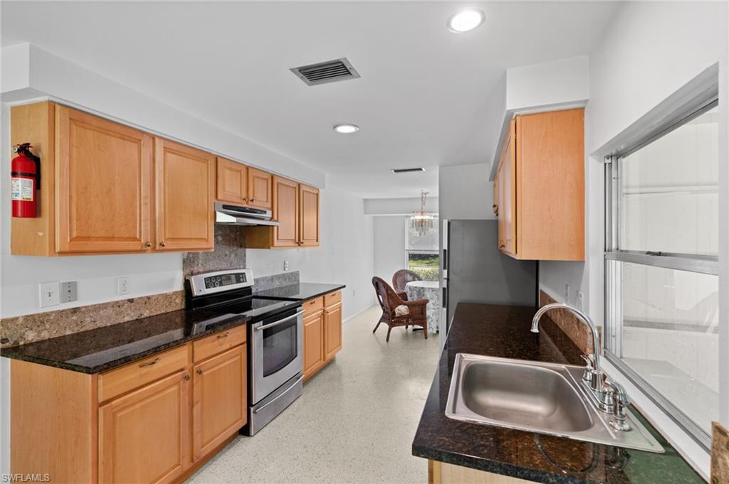 6 Maui Circle Naples, FL 34112 - Photo 10 of 22 a kitchen with stainless steel appliances granite countertop a sink stove and refrigerator