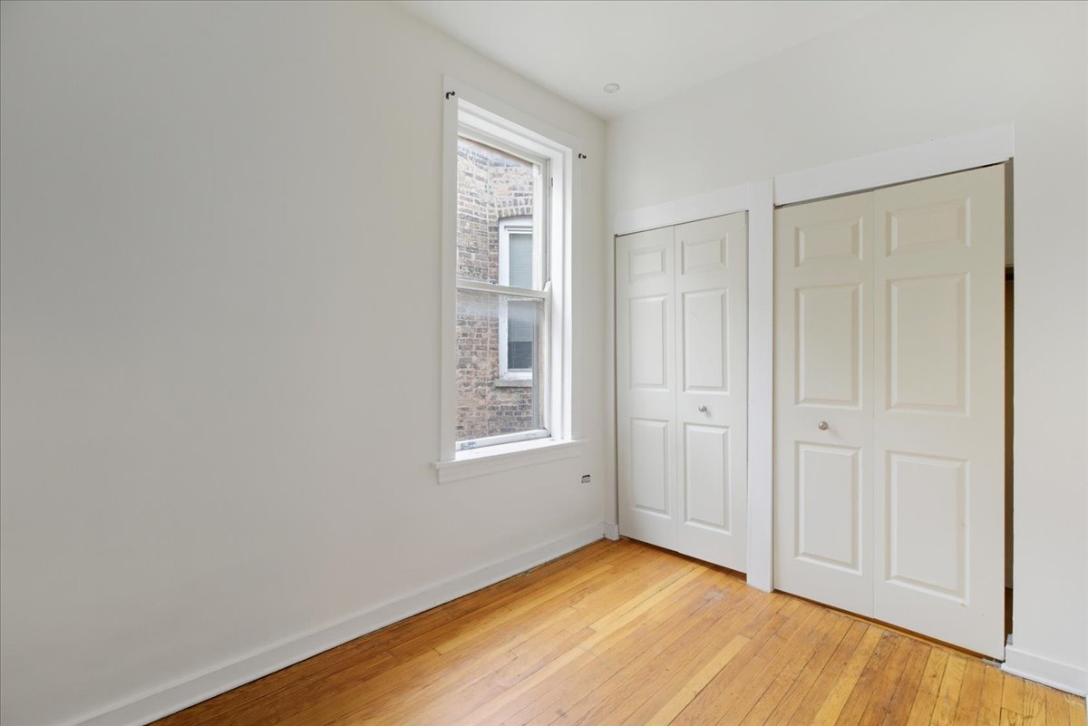 3133 West Augusta Boulevard, Unit 3E Chicago, IL 60622 - Photo 6 of 10 an empty room with wooden floor and windows