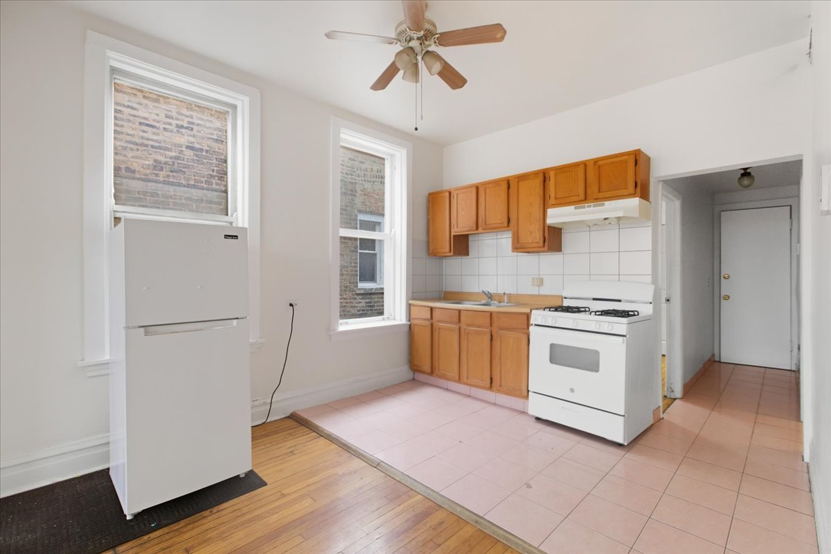 3133 West Augusta Boulevard, Unit 3E Chicago, IL 60622 - Photo 8 of 10 a kitchen with granite countertop a stove a sink and a refrigerator