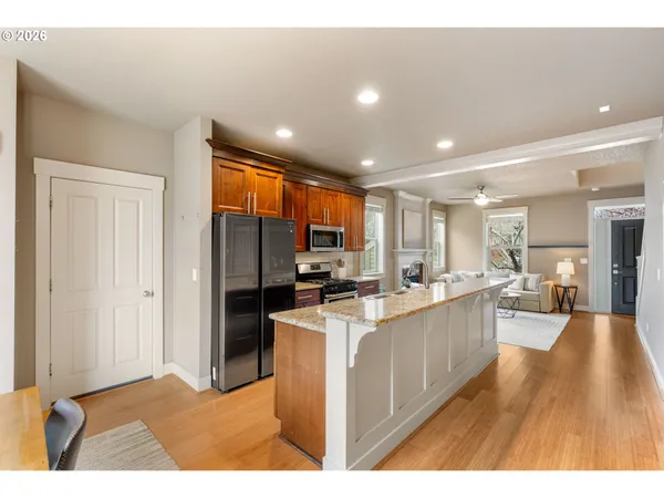 a open kitchen with stainless steel appliances kitchen island a sink dishwasher a refrigerator and a dining table with wooden floor