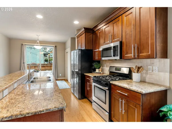 a kitchen with stainless steel appliances granite countertop a stove refrigerator sink and microwave