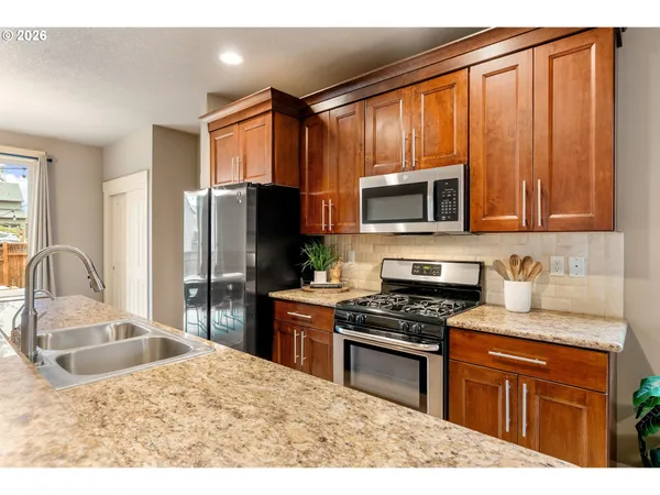 a kitchen with granite countertop wooden cabinets a refrigerator and a sink