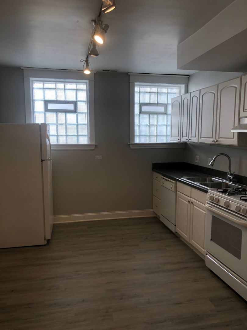 Undisclosed Address Chicago, IL 60613 - Photo 7 of 12 a kitchen with granite countertop wooden cabinets and a black wooden floor