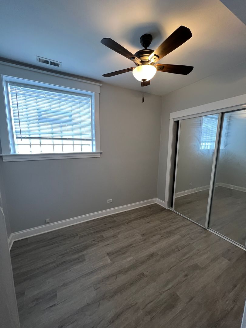 Undisclosed Address Chicago, IL 60613 - Photo 10 of 12 an empty room with wooden floor fan and windows