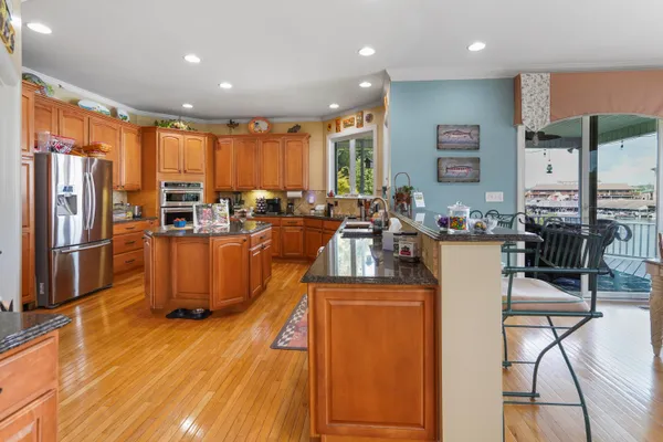 a kitchen with stainless steel appliances granite countertop a stove a sink and a refrigerator with wooden cabinets