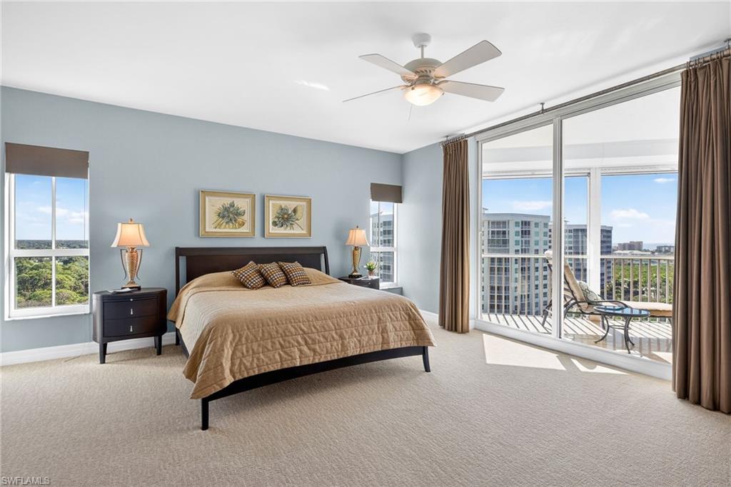 295 Grande Way, Unit 901 Naples, FL 34110 - Photo 16 of 50 a bedroom with a large bed and a chandelier fan
