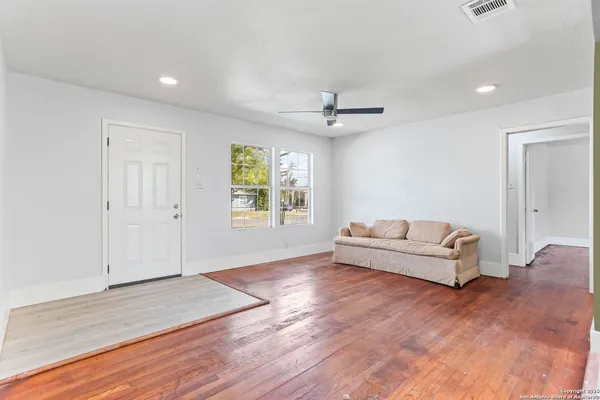 an empty room with windows and ceiling fan