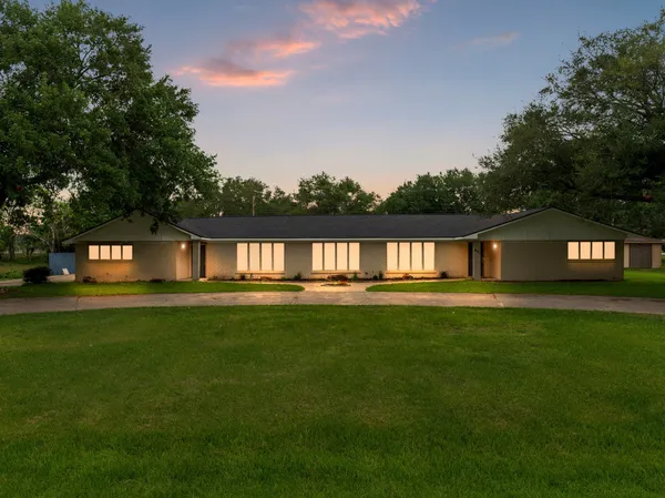 a view of a house next to a big yard with large trees