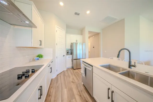 a large white kitchen with a lot of counter space and wooden floor