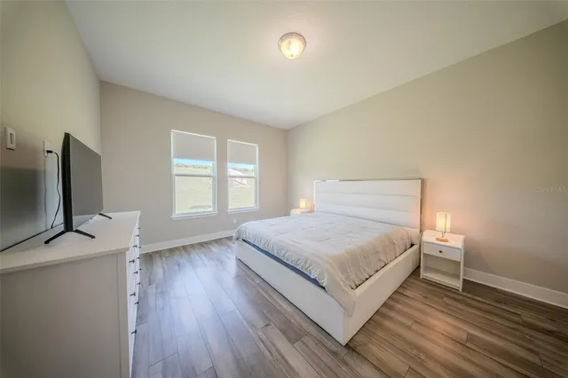 a spacious bedroom with a bed and a flat screen tv