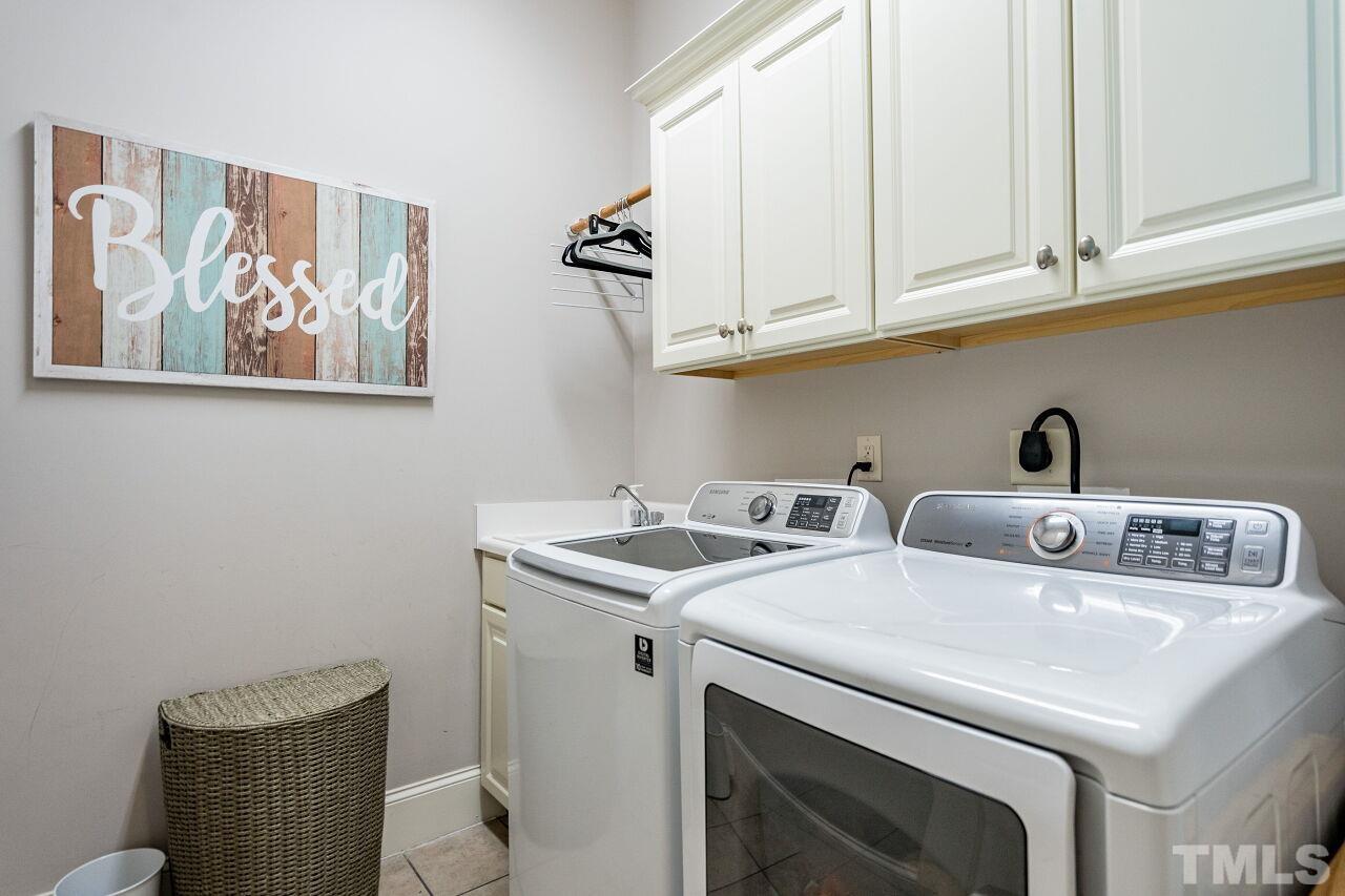 8035 Brandyapple Drive Raleigh, NC 27615 - Photo 21 of 30 First floor laundry room with sink, cabinets and tile floor.