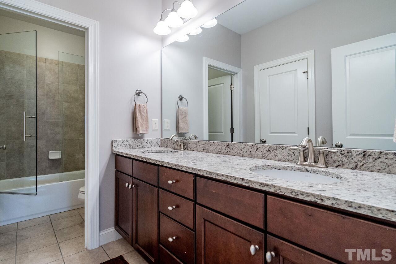 8035 Brandyapple Drive Raleigh, NC 27615 - Photo 25 of 30 Second floor bathroom with tub/shower, glass door, granite tops and tile floor.