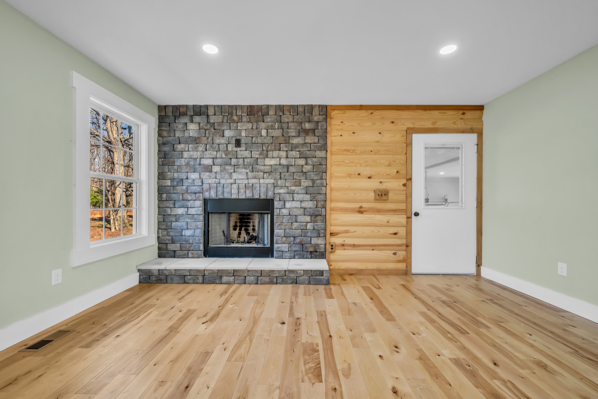 718 Darrell Rye Road Erin, TN 37061 - Photo 9 of 38 an empty room with wooden floor a fireplace and windows