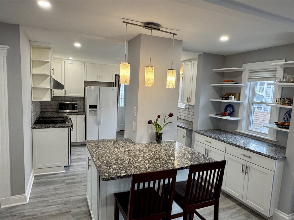 23 Drew Road, Unit 23 Belmont, MA 02478 - Photo 7 of 24 a kitchen with granite countertop a table chairs stainless steel appliances and cabinets