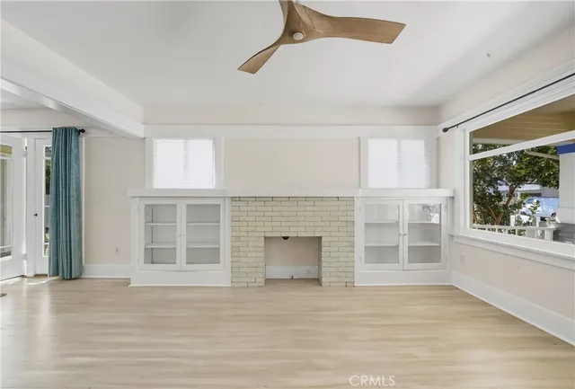 an empty room with wooden floor fireplace and windows