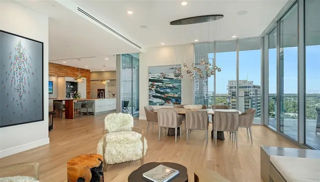 a living room with furniture potted plant floor to ceiling window and wooden floor