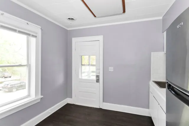 a view of an empty room with wooden floor and a window