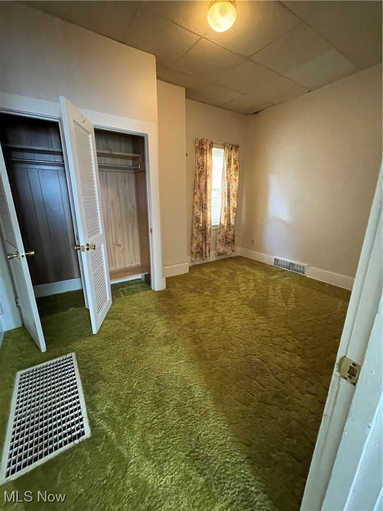 1881 Manchester Road Akron, OH 44314 - Photo 21 of 31 Unfurnished bedroom with two closets, carpet flooring, and a paneled ceiling