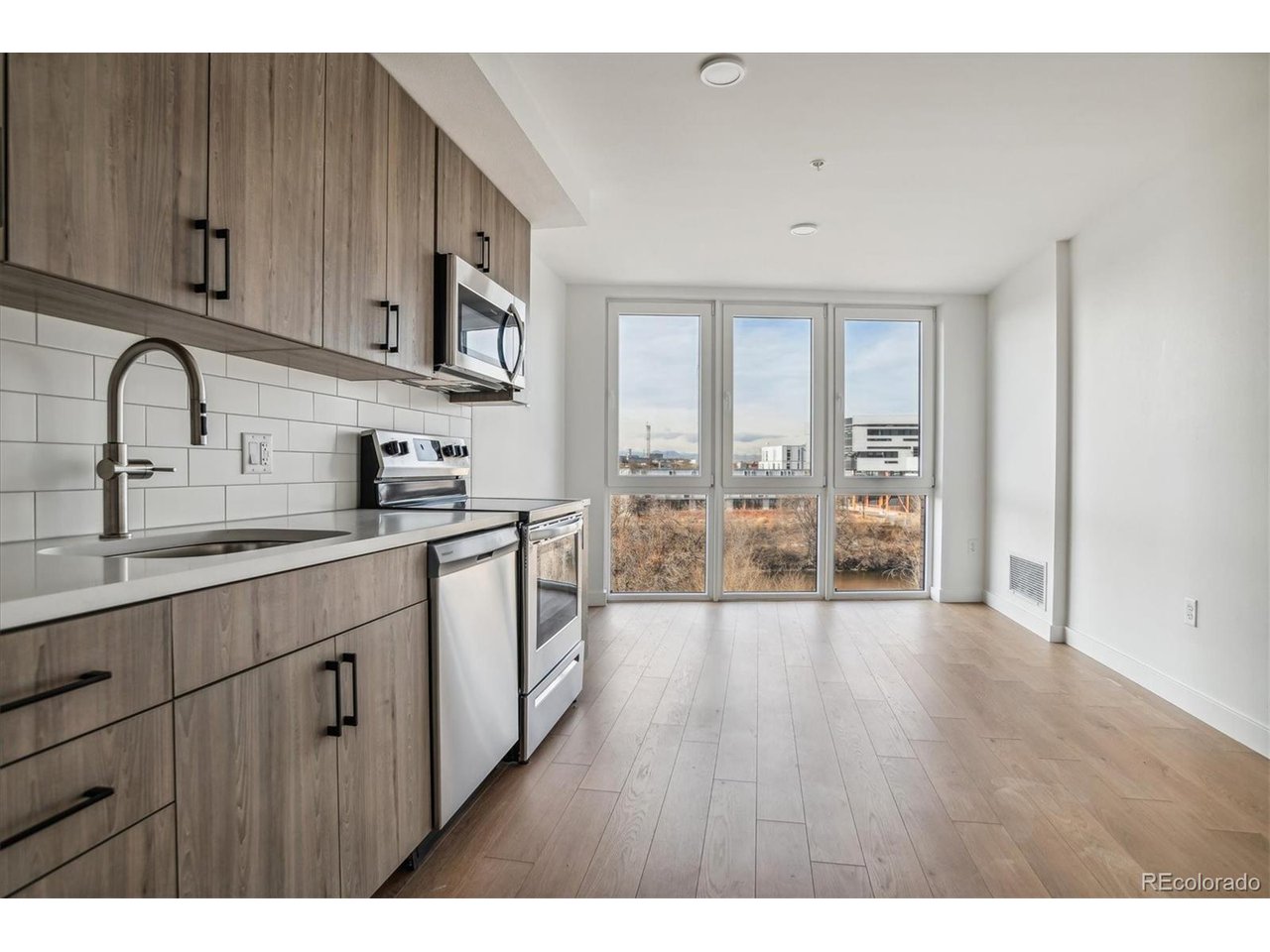 3575 Chestnut Place, Unit 406 Denver, CO 80216 - Photo 2 of 16 a large kitchen with stainless steel appliances granite countertop a stove a sink dishwasher and white cabinets with wooden floor