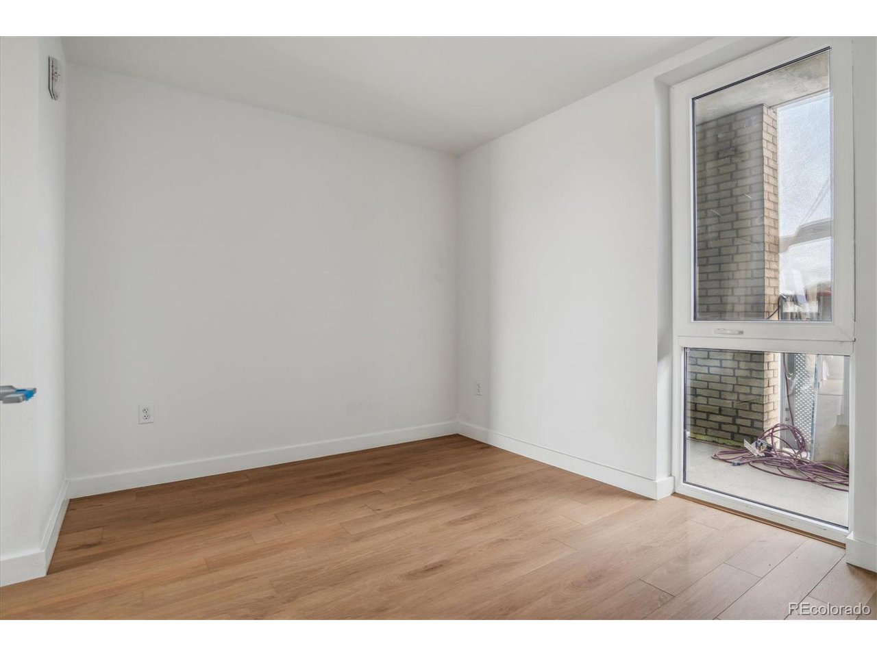 3575 Chestnut Place, Unit 406 Denver, CO 80216 - Photo 5 of 16 a view of an empty room with wooden floor and a window