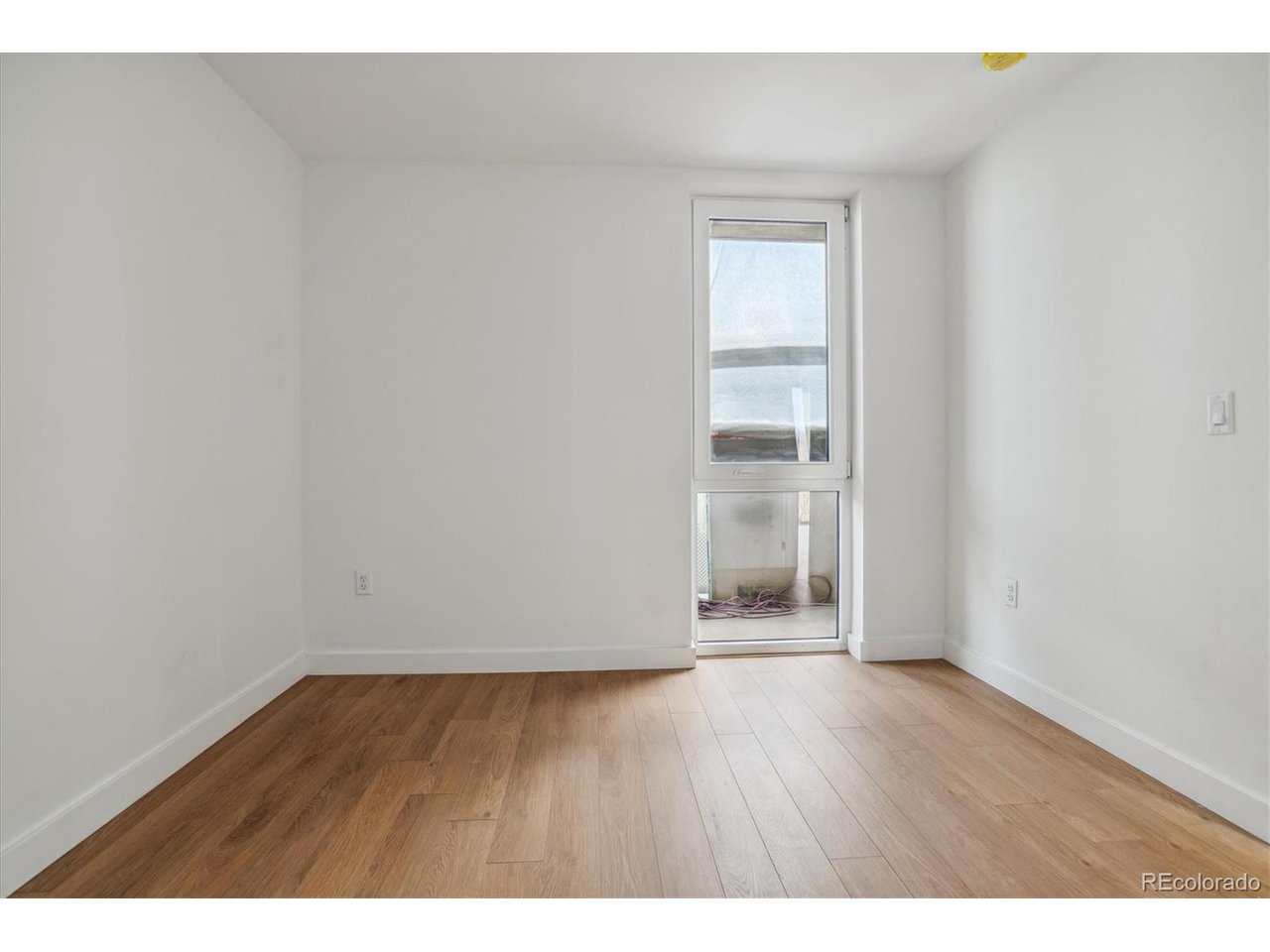 3575 Chestnut Place, Unit 406 Denver, CO 80216 - Photo 9 of 16 a view of an empty room with wooden floor and a window