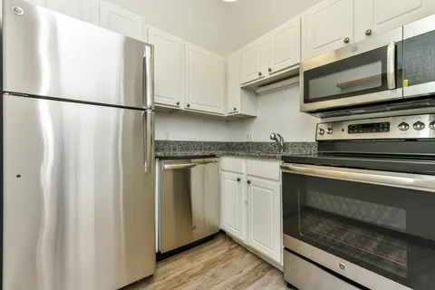 a kitchen with granite countertop white cabinets and stainless steel appliances