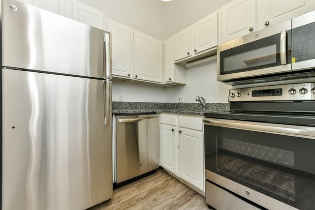 a kitchen with granite countertop white cabinets and stainless steel appliances