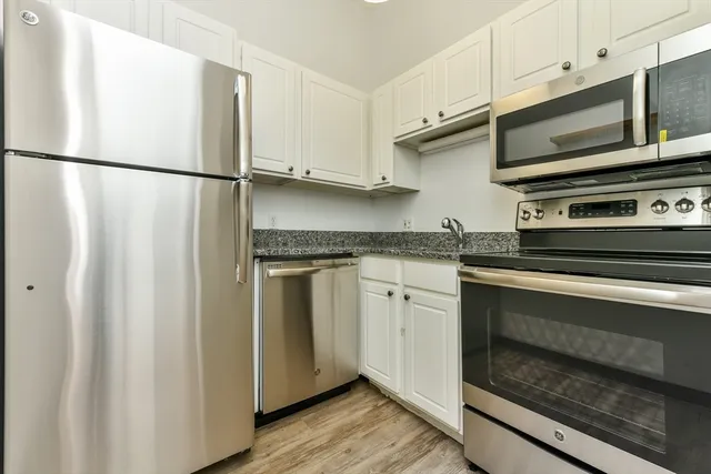 a kitchen with granite countertop white cabinets and stainless steel appliances
