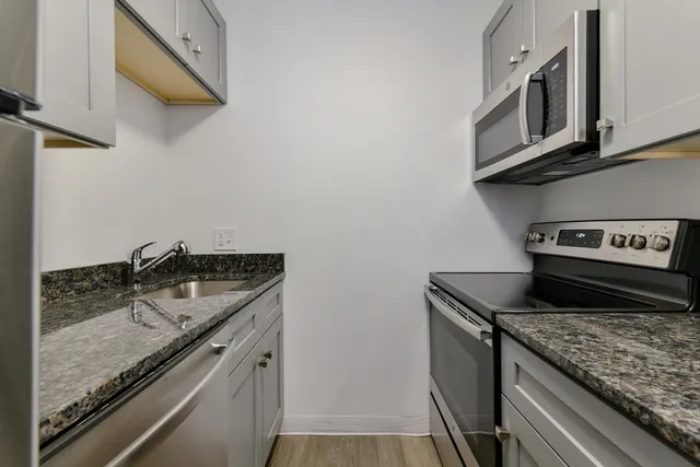 a kitchen with stainless steel appliances granite countertop a sink stove and cabinets