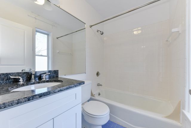 a bathroom with a granite countertop sink a toilet and shower