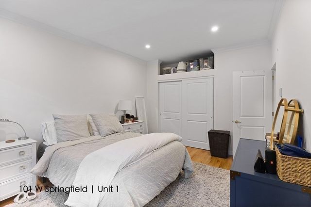 a spacious bedroom with a bed and wooden floor