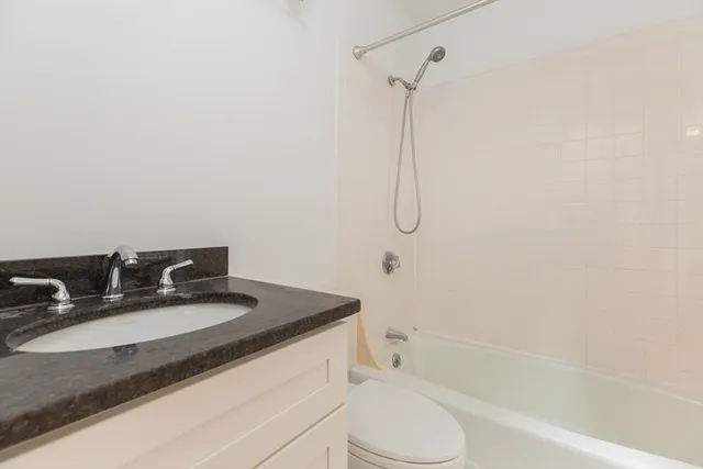 a bathroom with a granite countertop sink toilet and shower
