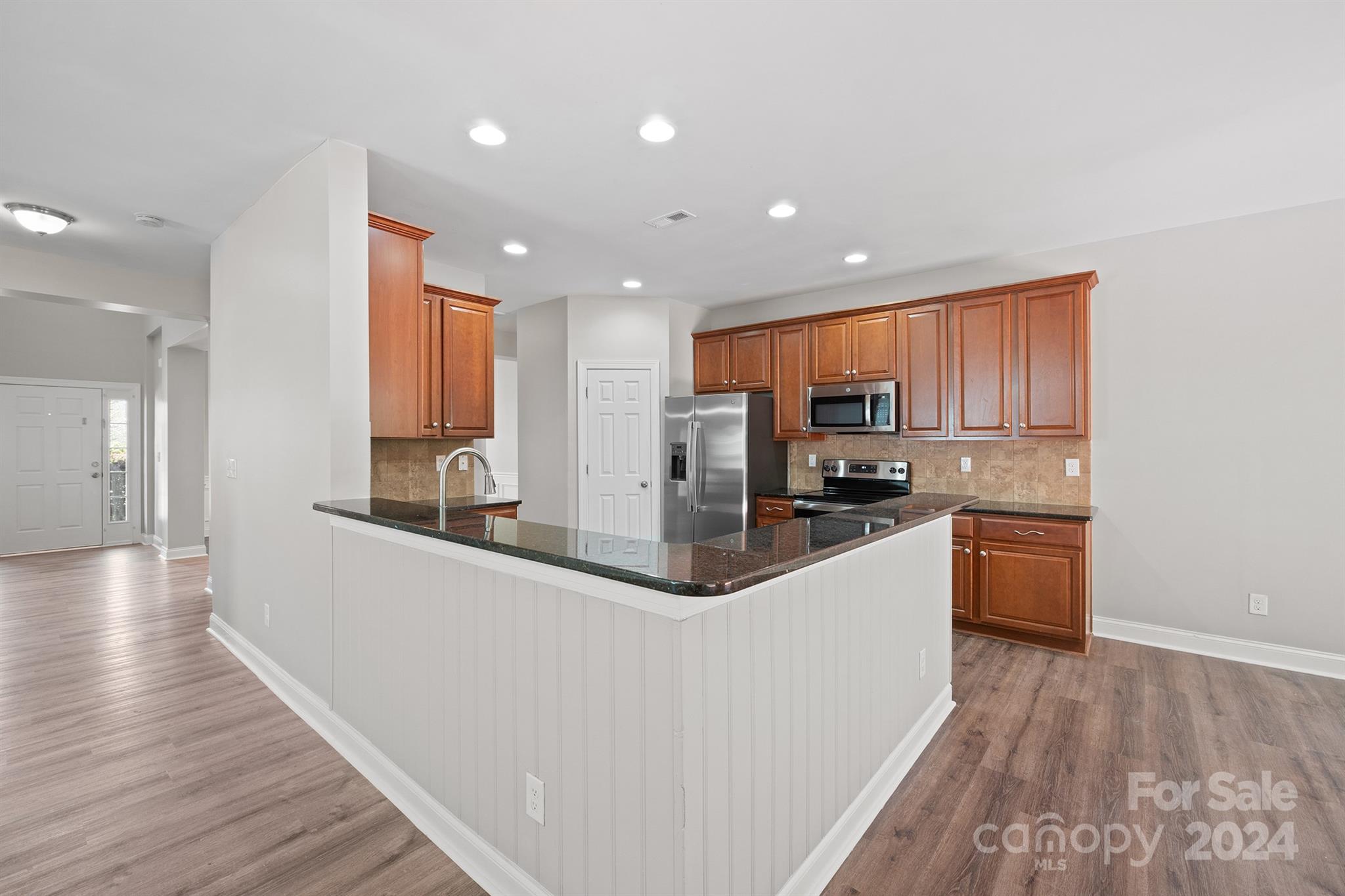 4009 Thorndale Road Indian Trail, NC 28079 - Photo 12 of 48 a kitchen with stainless steel appliances granite countertop a refrigerator a stove top oven a sink dishwasher and wooden cabinets with wooden floor