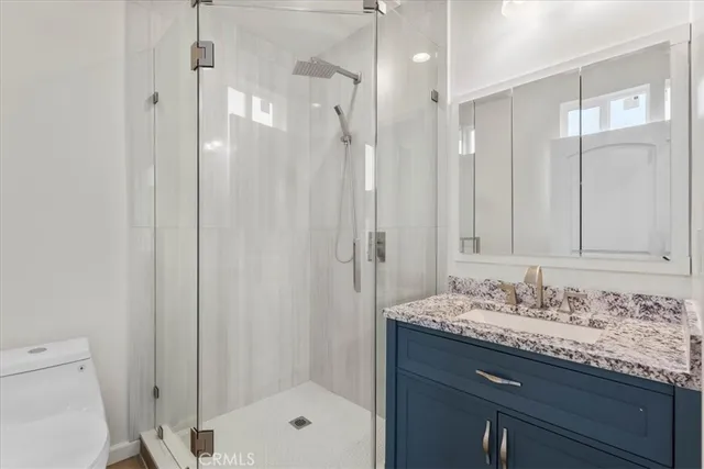 a bathroom with a granite countertop sink a mirror and a shower