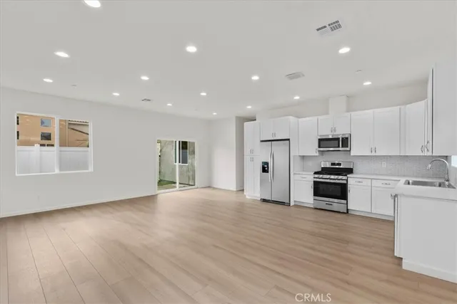 a view of kitchen with kitchen island wooden floors appliances and cabinets