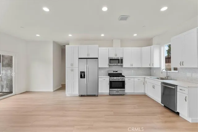 a large kitchen with stainless steel appliances granite countertop a stove a sink and a refrigerator