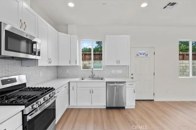 a kitchen with stainless steel appliances a sink cabinets and wooden floor