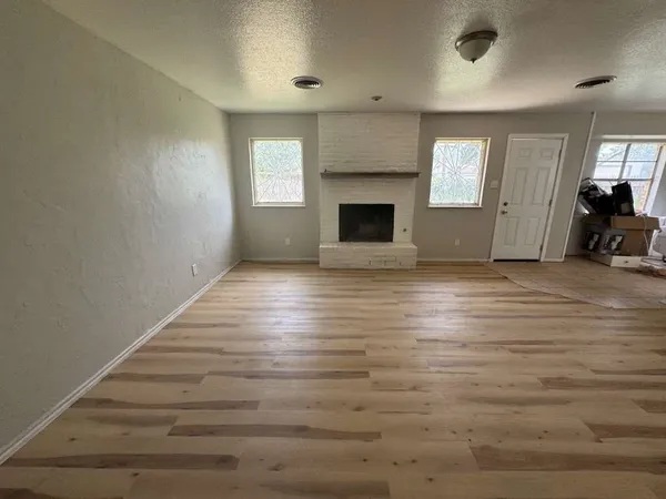 a view of empty room with fireplace and wooden floor