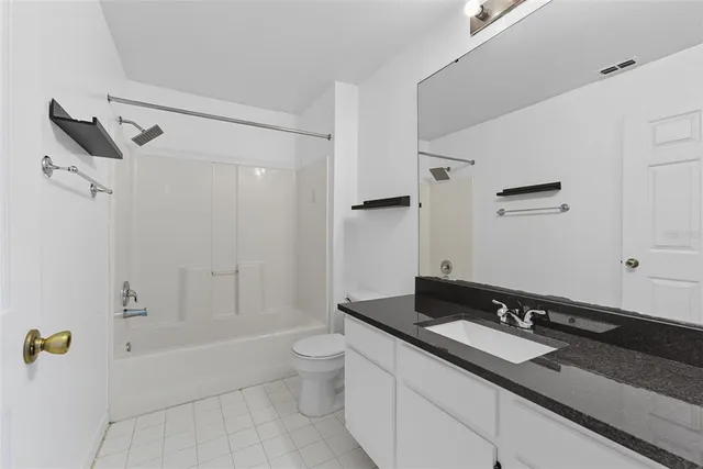 a bathroom with a granite countertop sink a toilet and shower