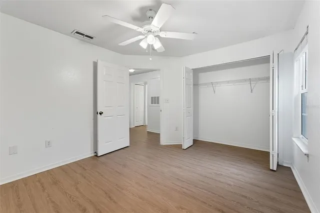 an empty room with wooden floor and a ceiling fan