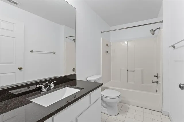 a bathroom with a granite countertop sink toilet a mirror a bathtub and shower