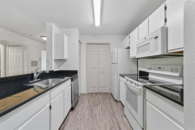 a kitchen with granite countertop a sink stove and cabinets
