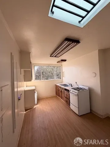 a kitchen with stainless steel appliances wooden floors and white walls